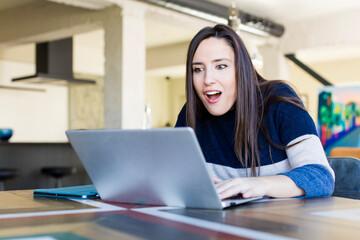 young adult pretty woman telecommuting with a laptop at home