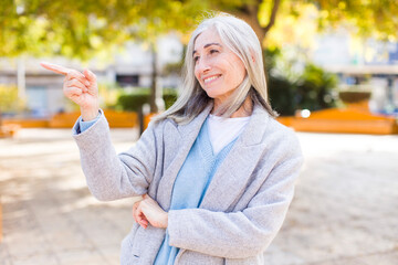 senior retired pretty white hair woman smiling happily and looking sideways, wondering, thinking or having an idea