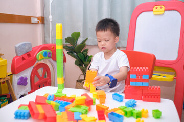 Toddler playing with toys, Cute smiling little Asian 5 years old toddler boy playing with colorful plastic building blocks indoor at home, Educational toys for young children, Soft and Selective focus