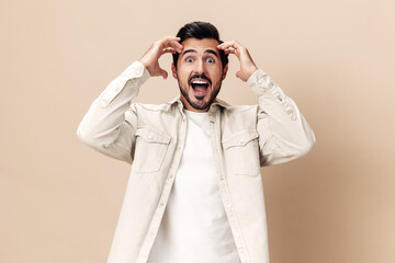 Portrait of a stylish man smile with teeth happiness opened his mouth in surprise on a beige background in a white t-shirt looks at the camera, fashionable clothing style, copy space, space for text