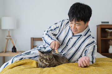 目が覚めてベッドで猫と戯れる50代男性
