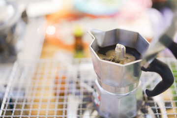 Brewing an espresso coffee in the traditional Moka pot during camping in forest or park.