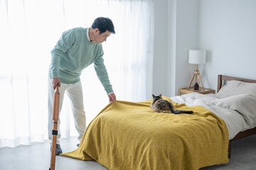 猫のいる寝室で掃除機をかける50代男性