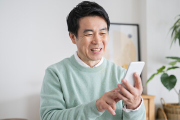 自宅でスマートフォンを使う50代男性