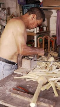 man carving wooden spoon in the patio of his house in colombia