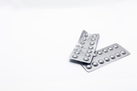 Two plastic blister-wrapped medicines is crumpled on a white background. Several packages of medicine are ripped off and there is a lot of empty space and copy space on one side.
