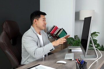 Naklejka premium Emotional boss having online meeting via computer at wooden table in modern office