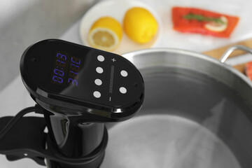 Sous vide cooker in pot on white table, closeup. Thermal immersion circulator