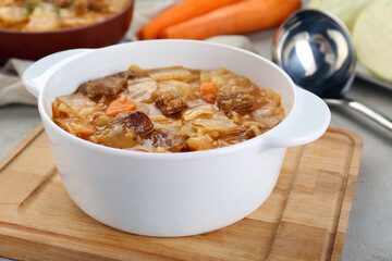 Tasty cabbage soup with meat and carrot on table, closeup