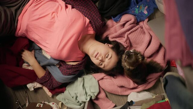 A girl with a dog in a wardrobe with clothes. A woman chooses T-shirts and throws them away. overcoming depression. High quality 4k footage