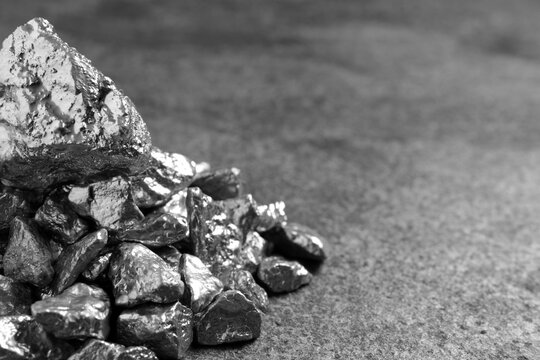 Pile of silver nuggets on grey textured table, closeup. Space for text