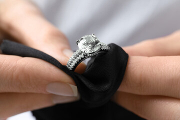 Jeweler cleaning diamond ring with microfiber cloth, closeup - obrazy, fototapety, plakaty