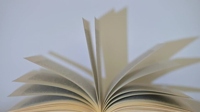 Open book with pages shadows moving against white background close-up view