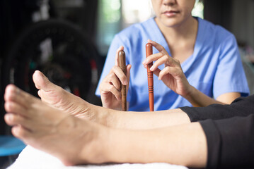 Obraz na płótnie Canvas Hands physiotherapist massaging with wood stick on feet,Reflexology spot thai foot massage