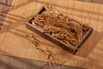 Angelica root putted on a wooden tray and bamboo blinds. People use Angelica root (Angelica sinensis) to beautify, improve health and treat circulatory as well as skin diseases