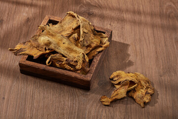 Rhubarb root and rhizome displayed on a wooden tray with wooden background. Rhubarb root and rhizome (Rhizoma Rhei) is mainly used to cure digestive problems