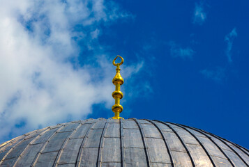 Fototapeta na wymiar Decorated roof of an ancient mosque against a blue sky with clouds