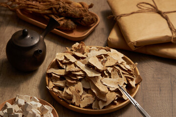 Bai Zhu putted on a dish with a tweezers, Poria cocos, Angelica root and a earthen pot displayed...