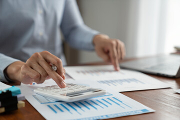 asian business man working with hand pointing graph discussion and analysis data charts and graphs and using a calculator to calculate numbers. Business finances and accounting concept.