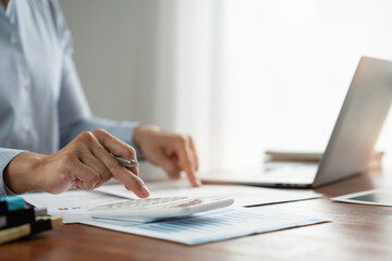 asian business man working with hand pointing graph discussion and analysis data charts and graphs and using a calculator to calculate numbers. Business finances and accounting concept.