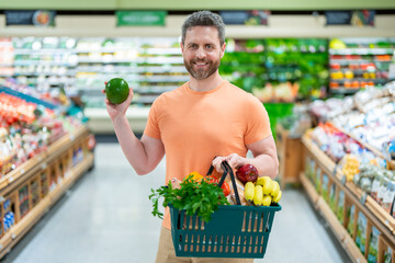 Man with grocery basket shopping at supermarket. Grocery store, shopping basket. Banner with man for grocery food store or supermarket. Man choosing food in store or grocery store.