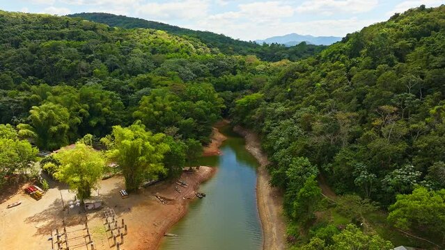 Fish farm along river crossing lush and tropical forest, Hatillo dam in Dominican Republic. Aerial forward