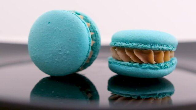 Blue macaroon isolated on white background two blue macaroons on a black plate with reflection one swirls the other lies motionless relationship delicious food breakfast lunch