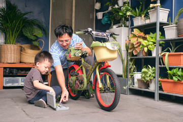 Happy Asian Father and son spend time together, Dad and son playing and repairing bicycle wheel,...