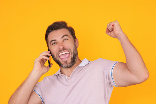 Excited man using smartphone, chatting, making post on social media. Guy call on phone isolated over studio background. Blogger talking on phone.