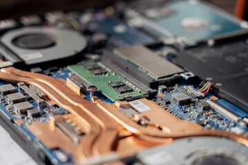 A technician repairs a broken laptop computer with a screwdriver. Notebook components and parts close-up
