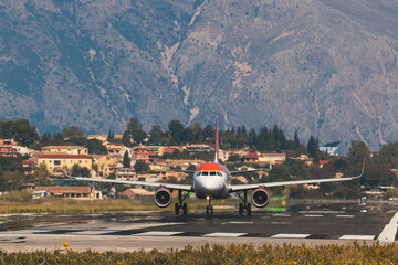 Fototapeta premium View of modern passenger plane aircraft on an runway airfield ready to take off, airstrip with commercial airplane before take off or after landing, airliner with mountains in a summer day