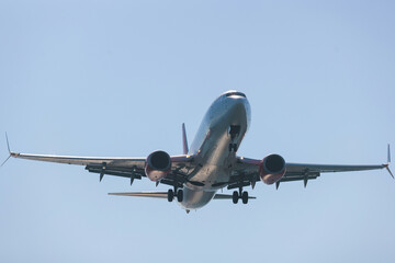View of modern passenger plane aircraft in flight, commercial airplane flying in the sky before take off or landing, with mountains in the background in a summer sunny day