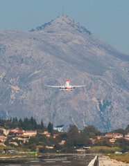 Fototapeta na wymiar View of modern passenger plane aircraft in flight, commercial airplane flying in the sky before take off or landing, with mountains in the background in a summer sunny day
