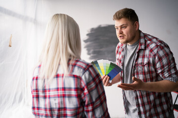 Fototapeta premium Angry couple arguing while choosing color samples at home. Home, moving, decoration, renovation, and wall painting concept