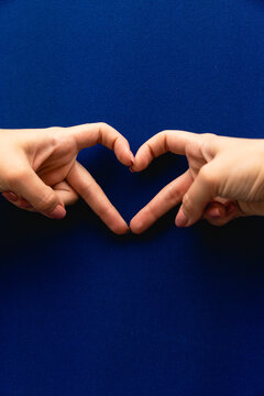 Female hands heart shape on blue background The hand gesture of a heart shape symbolizes love for Valentine's Day Hand gestures are a special language through which people can understand each other.