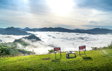 Fototapeta na wymiar The tables and chairs on the top of a high mountain and a beautiful view of the white cloud valley at Tak Po mountain, Quang Nam province, Vietnam. The soaring idea of freedom