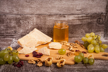 Cheese, grape, nuts and honey on vintage wooden background in studio photo