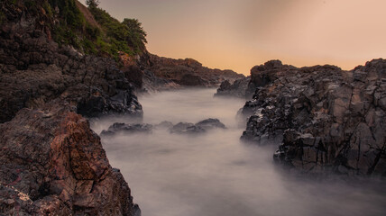 Fototapeta na wymiar sunset over ocean rocks long exposure