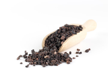 Himalayan black salt in a wooden spoon on a white background. Copy space.