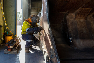 Angle grinding to repair an excavator's bucket inside a factory