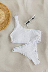 Beach accessories: swimsuit, sunglasses, hat, sandals with palm fronds and seashells. View from above on white background