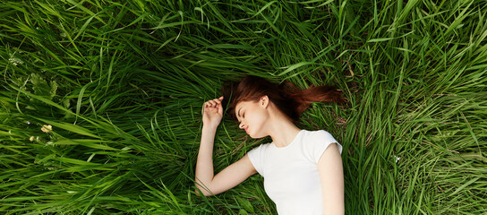 peaceful, happy woman lies in green tall grass