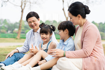 Fototapeta na wymiar image of an asian family sitting together on the grass at the park