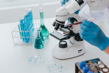Scientist or doctor wear medical protective mask looking at blood samples under microscope.