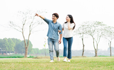 Naklejka na ściany i meble image of a happy asian couple in the park