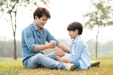 Obraz premium image of an asian father and son having fun in the park