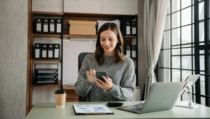 Confident business expert attractive smiling young woman typing laptop ang holding digital tablet  on desk in creative office.