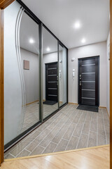 long corridor in interior of entrance hall of modern apartments with doors, cabinets, shelves and a mirror