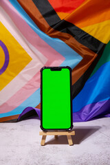 Mobile phone with chroma key on Rainbow LGBTQIA flag made from silk material background. Happy pride month. Symbol of LGBTQ pride month. Equal rights. Peace and freedom. Support LGBTQIA community