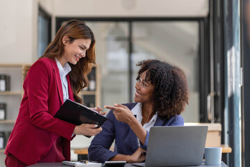 Two business people talk project strategy at office meeting room. Businessman discuss project planning with colleague at modern workplace while having conversation and advice on financial data report.